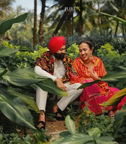 A happy, candid moment between Kulneet and Prabhleen, framed by large green leaves. This shot shows how we capture genuine interactions even within a styled set.
