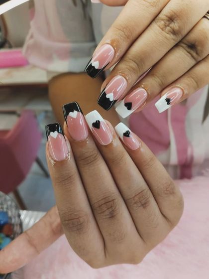 A cute and modern design featuring black and white French tips. The tiny hand-painted hearts at the base add a sweet, playful detail.
