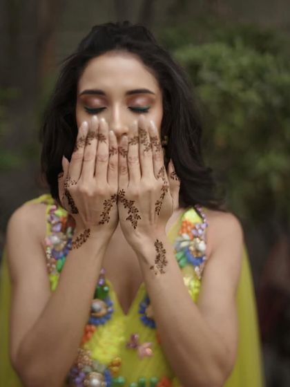 A beautiful shot focusing on the bride's minimal and elegant mehendi design, with her makeup kept fresh and radiant.