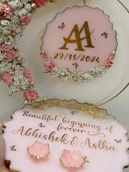 A pretty pink ring platter with a floral moon hoop and butterfly details. The couple's initials and date are featured on the hanging piece.