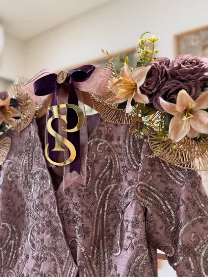 The intricate silver embroidery on this mauve outfit is highlighted with deep purple ribbons and delicate floral accents, creating a look of pure elegance.