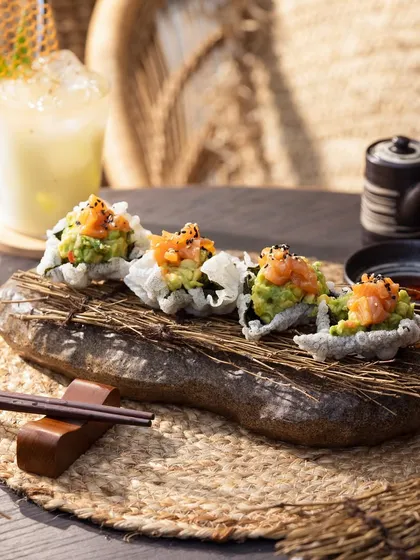 Crispy rice topped with salmon and avocado. The rustic stone platter and natural lighting give this a fresh, organic feel.