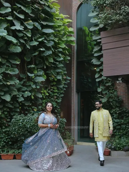 A playful wedding portrait with the bride in the foreground and the groom walking towards her, creating a sense of story and movement.