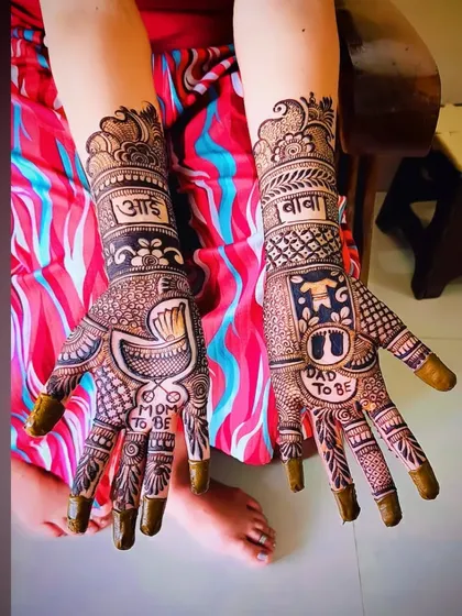 This angle highlights the central elements of the baby shower mehandi, with the cradle on one palm and the baby clothes on the other.
