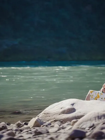 A wide shot capturing the couple in a beautiful natural landscape, sitting by the river. This showcases my ability to shoot in diverse, scenic locations.