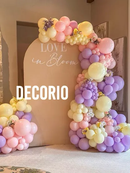 A beautiful 'Love in Bloom' themed setup with a pastel balloon garland in shades of pink, purple, and yellow. The soft colors and floral accents create a romantic and whimsical ambiance.