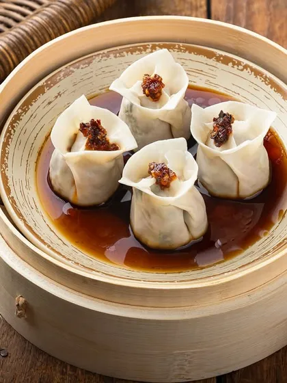 Steamed chicken dim sum presented in a traditional bamboo steamer. The lighting is carefully controlled to highlight the delicate texture of the wrapper and the savory filling, demonstrating a clean approach to Pan-Asian food photography.