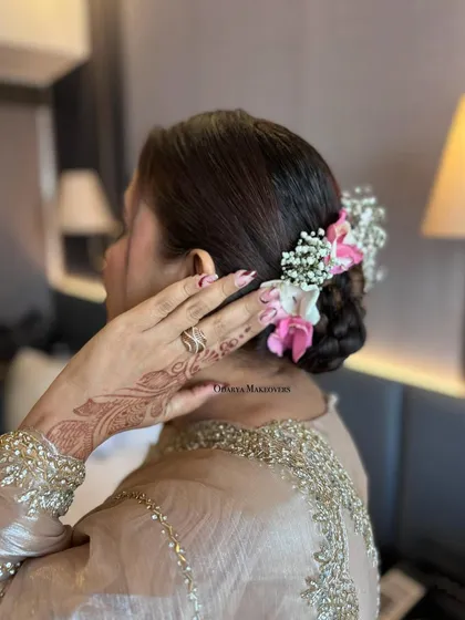 A delicate floral bun for this wedding guest. The fresh flowers add a touch of softness and romance to the hairstyle.