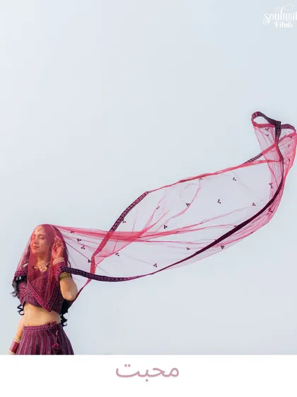 A dramatic shot of the bride with her veil flowing in the wind. The minimalist background and the single word "Mohabbat" (Love) make this a powerful and artistic statement.