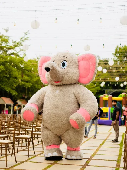 A friendly elephant mascot walking through the party venue, ready to entertain the kids and pose for photos at Eshaan's safari celebration.