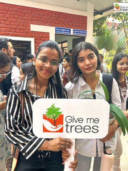 Two college students hold our banner and a plant, symbolizing their commitment to a greener future after our interactive session.