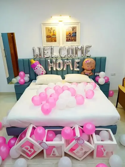 A sweet 'Welcome Home' bedroom decoration for a baby girl, with pink and white balloons and 'BABY' boxes.