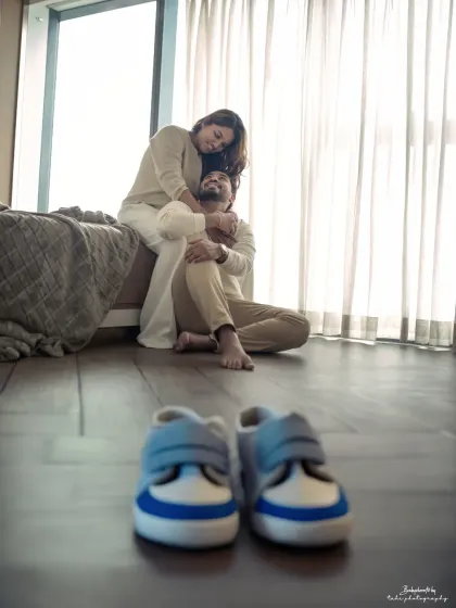 A beautifully composed shot focusing on a pair of baby shoes, with the expectant couple sharing a loving moment in the background. It’s a perfect pregnancy announcement photo.