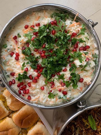 A bowl of creamy curd rice garnished with fresh coriander and pomegranate seeds.