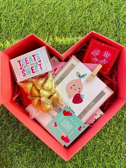 The heart-shaped Valentine's box opened to show the gifts inside. It's a sweet surprise with chocolates and cute, personalized cards.