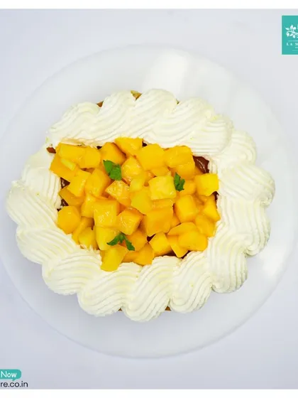 An overhead view of our seasonal Mango Cheesecake. We use a creamy, rich cheesecake base and top it with fresh, sweet mango chunks for a perfect tropical dessert.