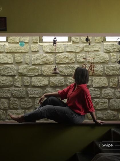 A resident enjoying a moment of peace on a wide window ledge next to an exposed stone wall, a signature feature that brings natural texture indoors.