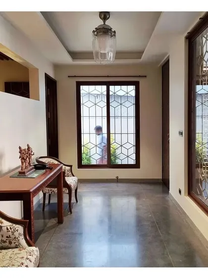 The geometric pattern from the main door is carried through to the window grills, creating a cohesive design language for the home's exterior.