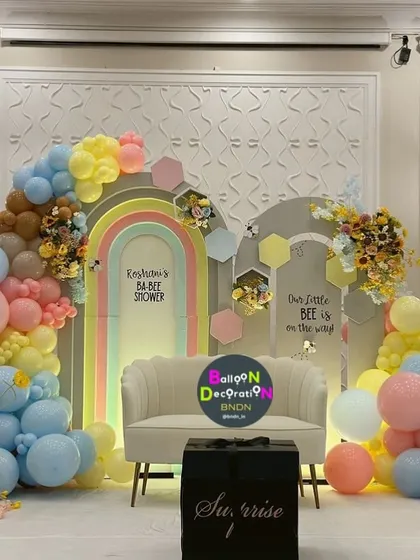 A vibrant and colorful baby shower combining a rainbow arch with a "little bee is on the way" theme, showing how we can merge ideas.