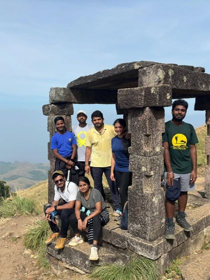 A group resting at the ancient stone Mantapa on the way to Kumara Parvatha peak. These structures provide a glimpse into the history of this trail.