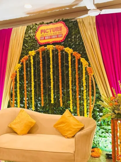 For a traditional Godh Bharai with a twist, we designed this vibrant 'Filmy' theme. The combination of a lush green wall, bright marigold garlands, and dramatic draping creates a festive and uniquely Indian celebration space.