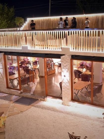 A view from the outside looking into the cafe, with guests visible on the rooftop terrace. The multi-level design offers different perspectives and experiences.