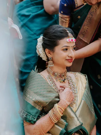 A beautiful Telugu wedding look. The bride's makeup is soft and radiant, with a touch of shimmer on the eyes and a warm lip colour that harmonizes with her gold saree and traditional jewellery.