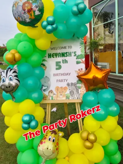 A personalized welcome sign on an easel, decorated with a balloon garland and animal foils, is the perfect way to greet guests at a jungle-themed party.