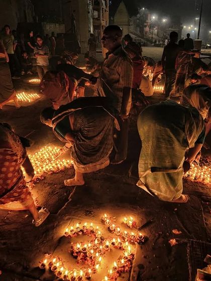 Devotees lighting diyas on the steps of the ghat. This photo captures the personal and collective act of devotion that defines Dev Deepawali.