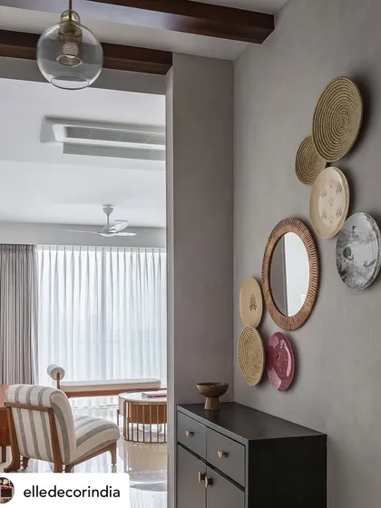This shot from our Elle Decor feature on 'House Nandini' showcases the entrance foyer. We curated a gallery wall of decorative plates and a rattan mirror to add texture and cultural context, creating a warm welcome.