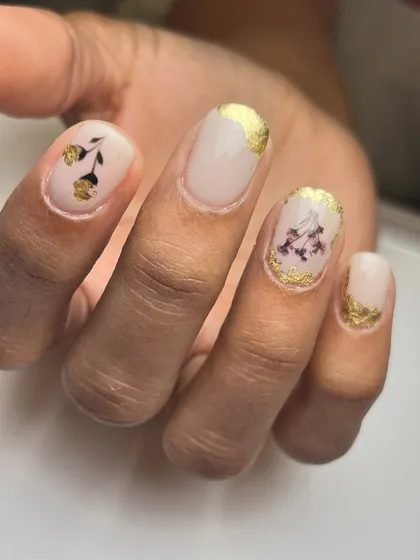A detail shot of the dried flower and gold foil nail art, showing how these elements are encapsulated for a durable and beautiful finish.