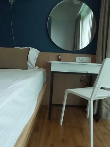 This bedroom setup includes a compact study or dressing table integrated with the headboard panel. It's a space-efficient solution that maintains a clean, cohesive look.