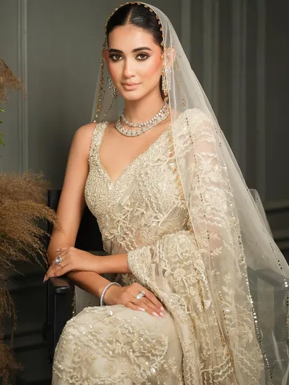 An elegant seated portrait in a beautiful ivory and gold creation by Nitika Gujral. The sheer dupatta and delicate embroidery create a look of soft, ethereal beauty.