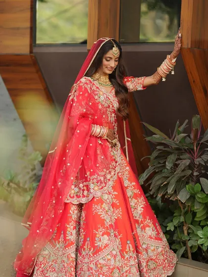 A candid, happy moment of the bride outdoors. The natural light enhances her radiant makeup and the beautiful embroidery on her lehenga.