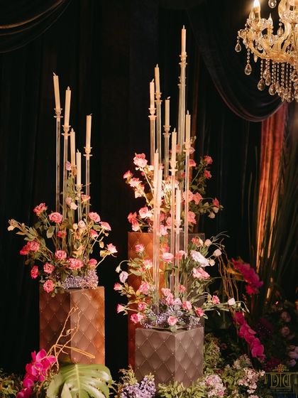 Tall, modern candelabras paired with soft pink floral arrangements added a touch of contemporary elegance to the masquerade sangeet. The contrast between the dark, moody drapes and the delicate flowers created a visually stunning effect.