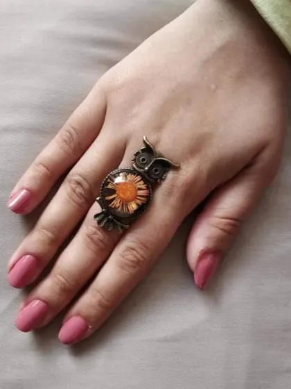 This good luck owl ring is a unique and stylish accessory. It features a real pressed orange flower set in resin, with an adjustable antique-finish owl frame. The flower color can be customized to your preference.