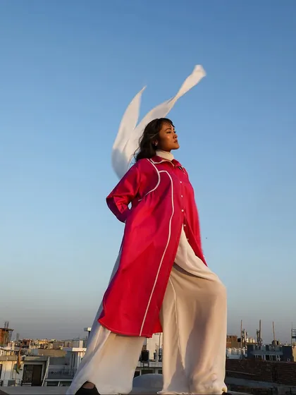 A dramatic outdoor shot of the fuchsia and white ensemble, with the scarf flowing in the wind, creating a powerful and free-spirited image.