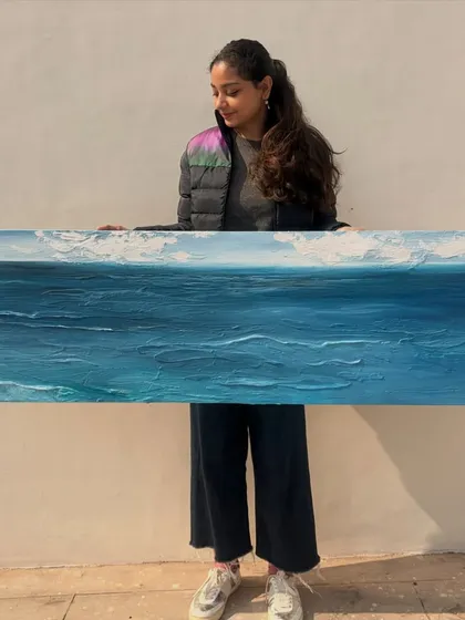 Here I am with a custom seascape painting just before it was shipped to Kolkata. I'm obsessed with painting water, and I use texture to capture the movement of the waves. This piece shows the scale of my work and my passion for bringing nature indoors.