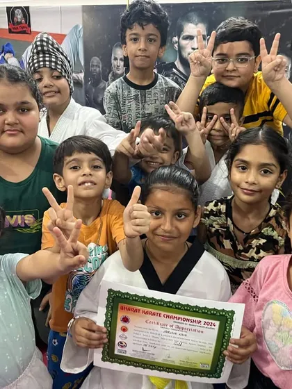 The whole team celebrates a student's achievement. She holds her certificate from the Bharat Karate Championship, surrounded by her training partners.