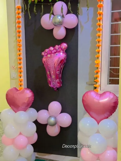 I love decorating doors to welcome the little ones. This design features pink and white balloon pillars, heart-shaped foil balloons, and a baby foot foil balloon as the centerpiece.