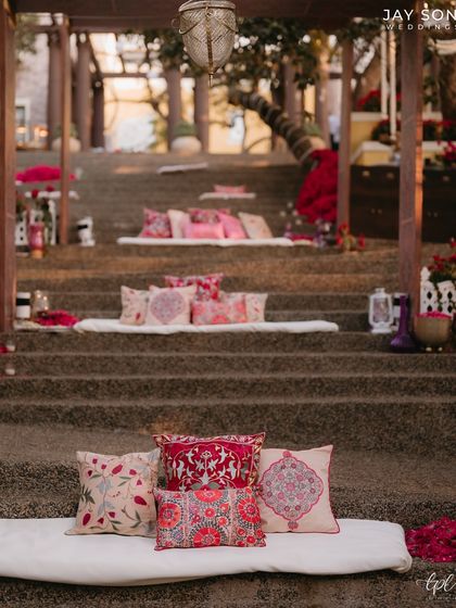 Unique tiered seating for the Mehfil-e-Mehendi, where mattresses and vibrant cushions are placed on stone steps, creating a relaxed and communal amphitheater-style lounge.