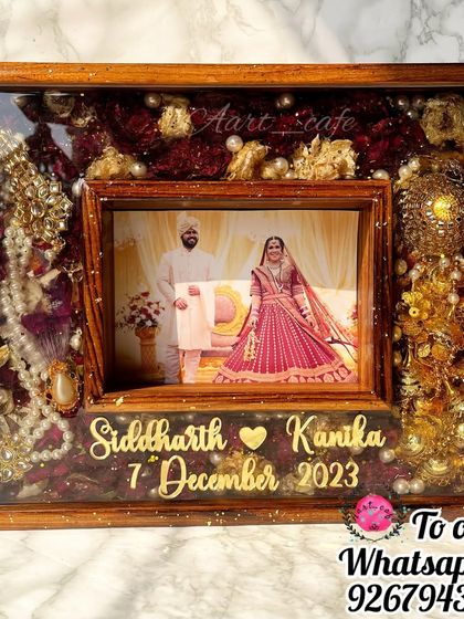 A full view of the popular photo-changing frame, customized with the couple's names and wedding date. The dark wood and rich red flowers give it a royal feel, perfect for preserving varmala, kalangi, and kaleera.