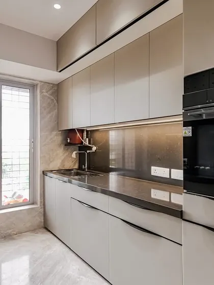 A view of the kitchen from the window side, showing the built-in oven and the natural light that fills the space.
