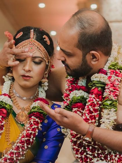 A tender moment as the groom applies sindoor, a key ritual in a Hindu wedding. Our candid photography focuses on the intimacy of these traditions.