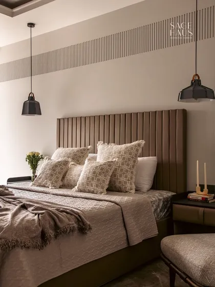 A wide shot of this calming bedroom retreat, showing the symmetry of the pendant lights and bedside tables. The layered bedding and plush pillows add to the feeling of comfort and understated luxury.