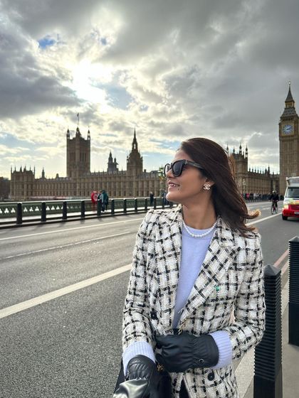 A quintessential London moment on Westminster Bridge with Big Ben in the background. I'm wearing a classic tweed coat dress with thigh-high boots, a perfect outfit for exploring the city in style during the cooler months.