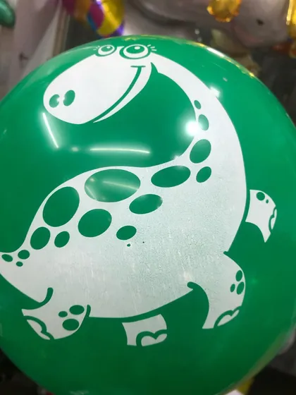 A close-up of our green latex balloon with a friendly dinosaur print, perfect for a jungle or dinosaur-themed party.