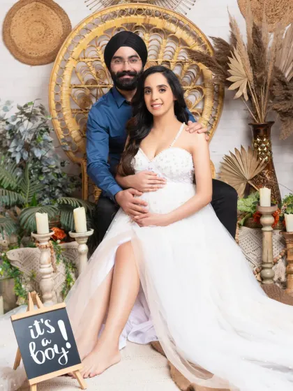 A joyful announcement in our bohemian set. The couple proudly displays an "It's a boy!" sign, their smiles radiating happiness.