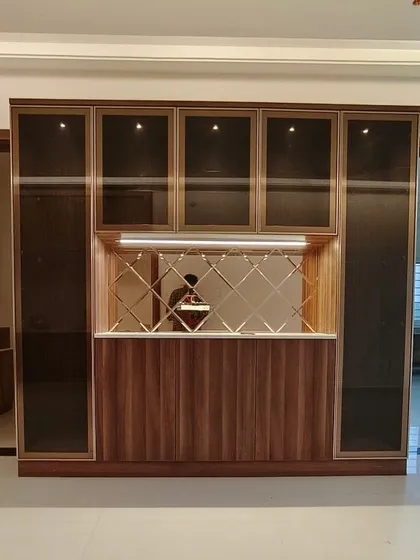 This is a crockery unit I designed to double as a stylish bar and serving counter. It combines tinted glass display cabinets, a mirrored backsplash, and closed wooden storage for a complete solution.