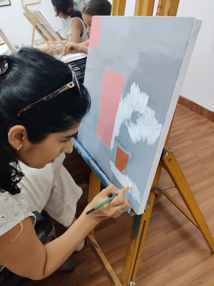 This series captures an adult student working on two different acrylic paintings, one a floral doorway and the other an abstract piece, showing the variety of styles we teach.